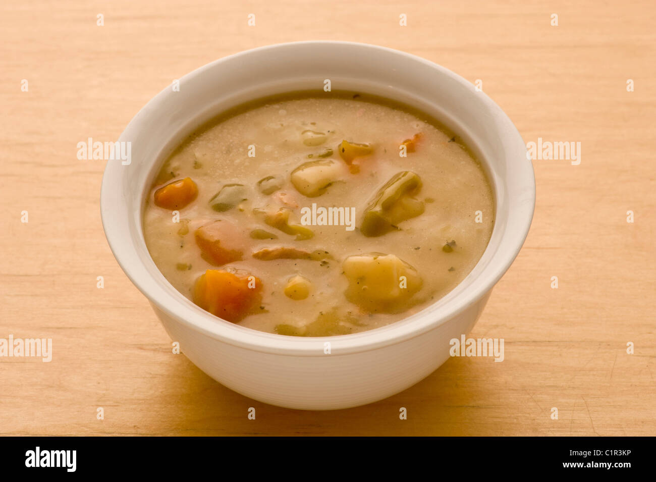 Vegetable soup in a ceramic white bowl on a wooden background. Stock Photo