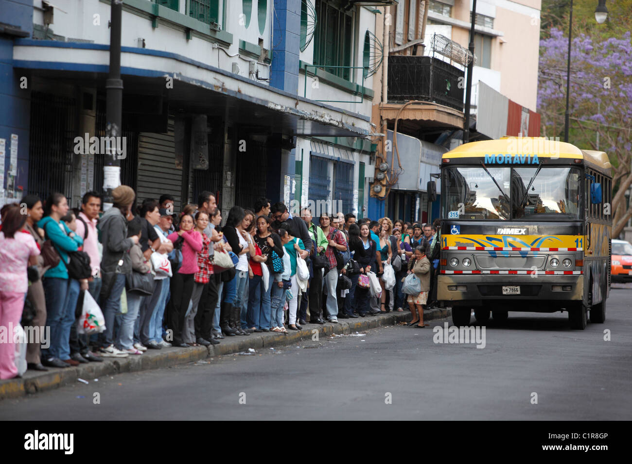 People queue at a bus stop, San Jose, Costa Rica Stock Photo