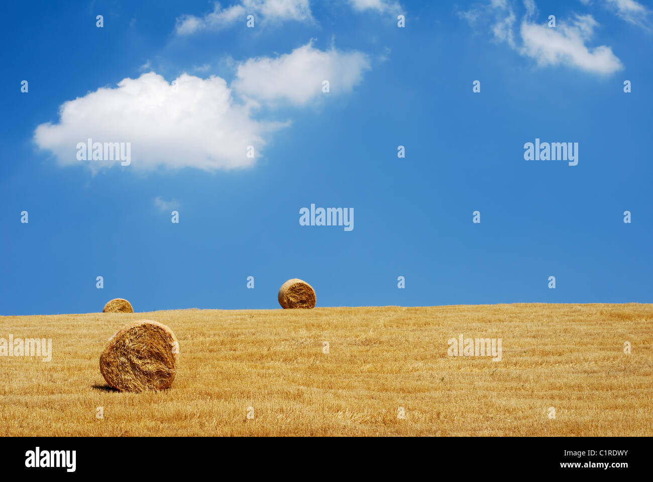 Three straw bales in a field with blue and white sky Stock Photo - Alamy