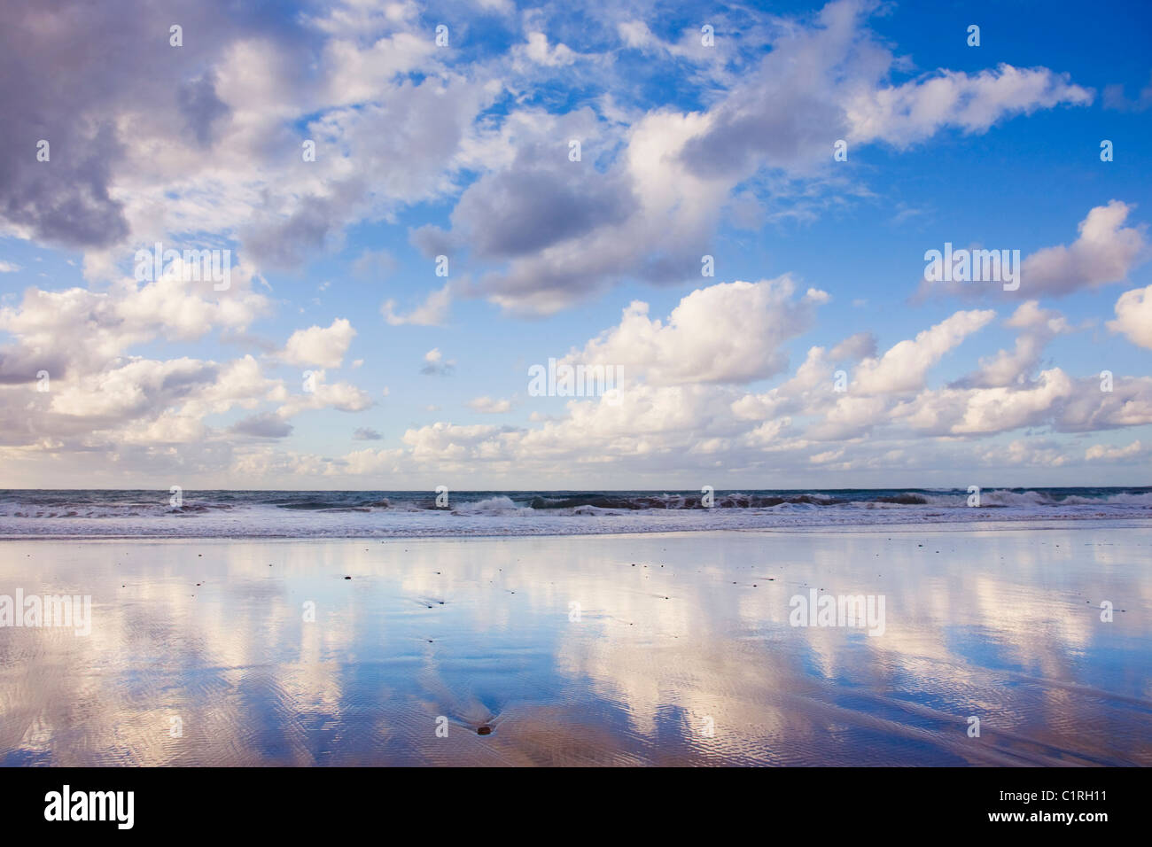 Blue sky and clouds reflected on a sandy beach Stock Photo