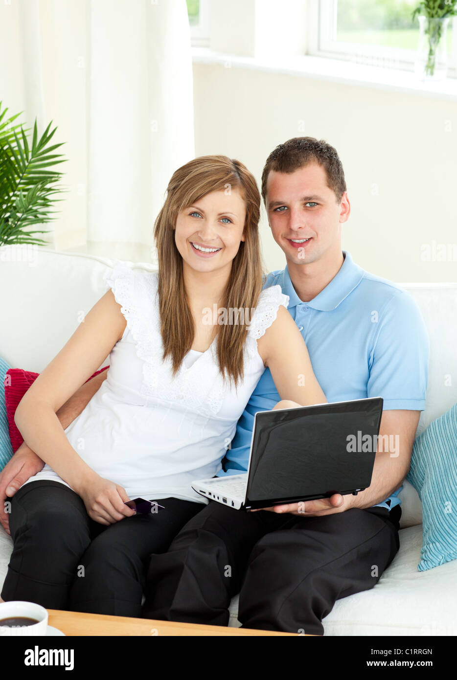 Enthusiastic couple using laptop smiling at the camera Stock Photo - Alamy