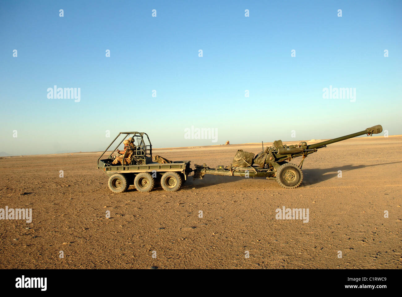 A 105mm light gun being towed by an all-terrain vehicle. Stock Photo