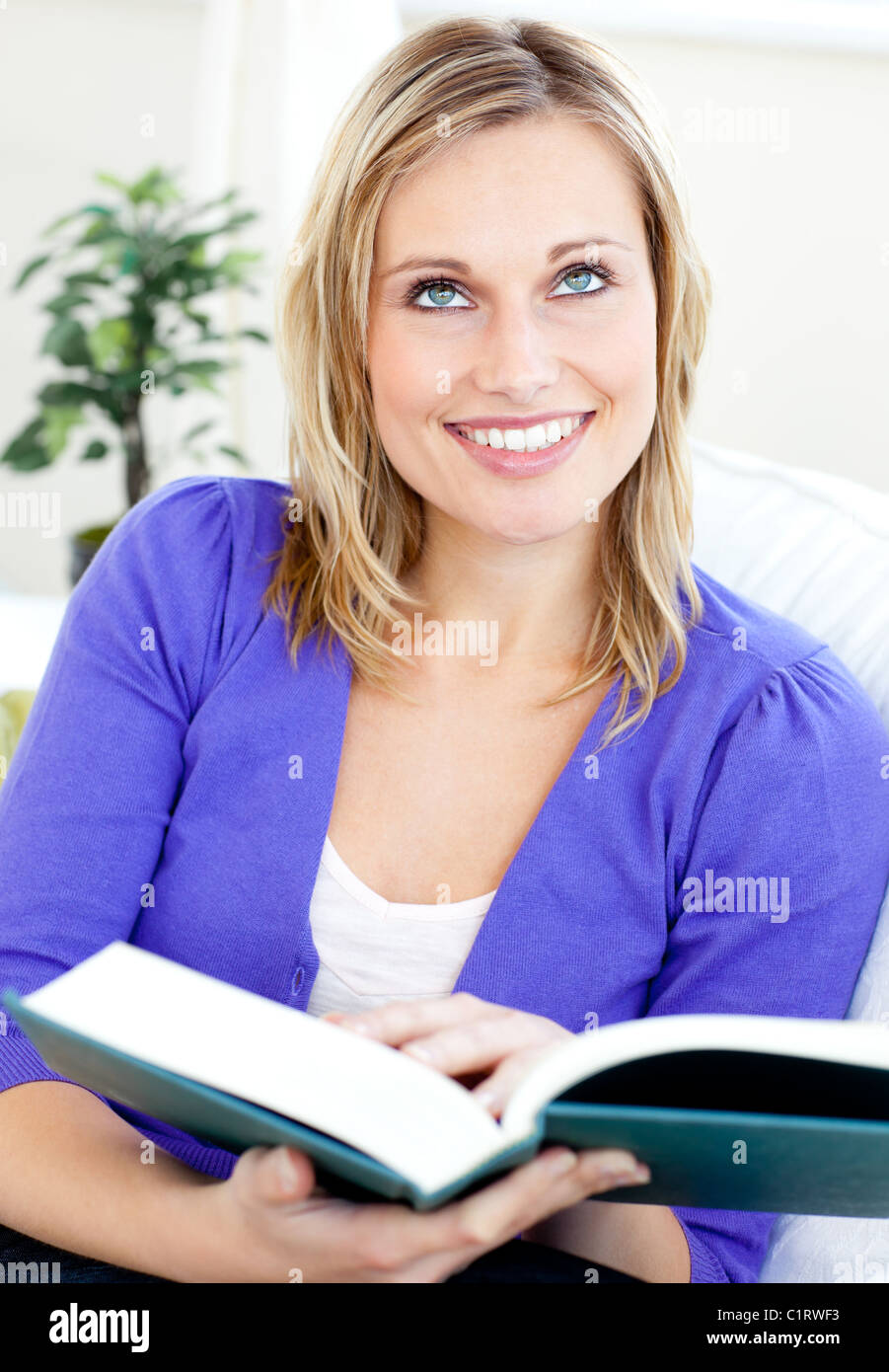 Bright caucasian woman reading a book sitting on a sofa Stock Photo - Alamy