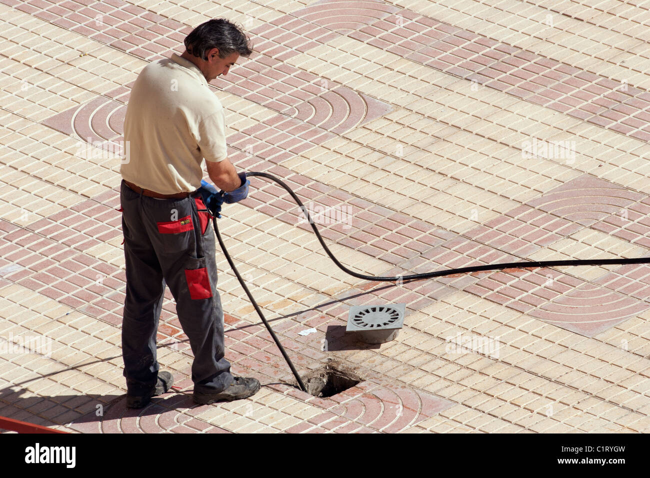 Plunger man clearing a clogged sewer Stock Photo
