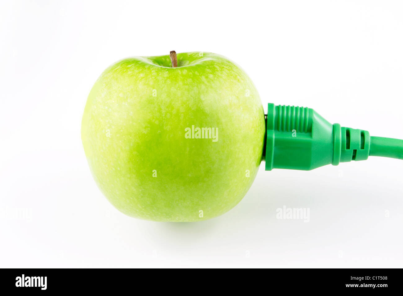 Green apple with electric plug inserted in its side suggests the strong need for creative green energy technologies. Stock Photo