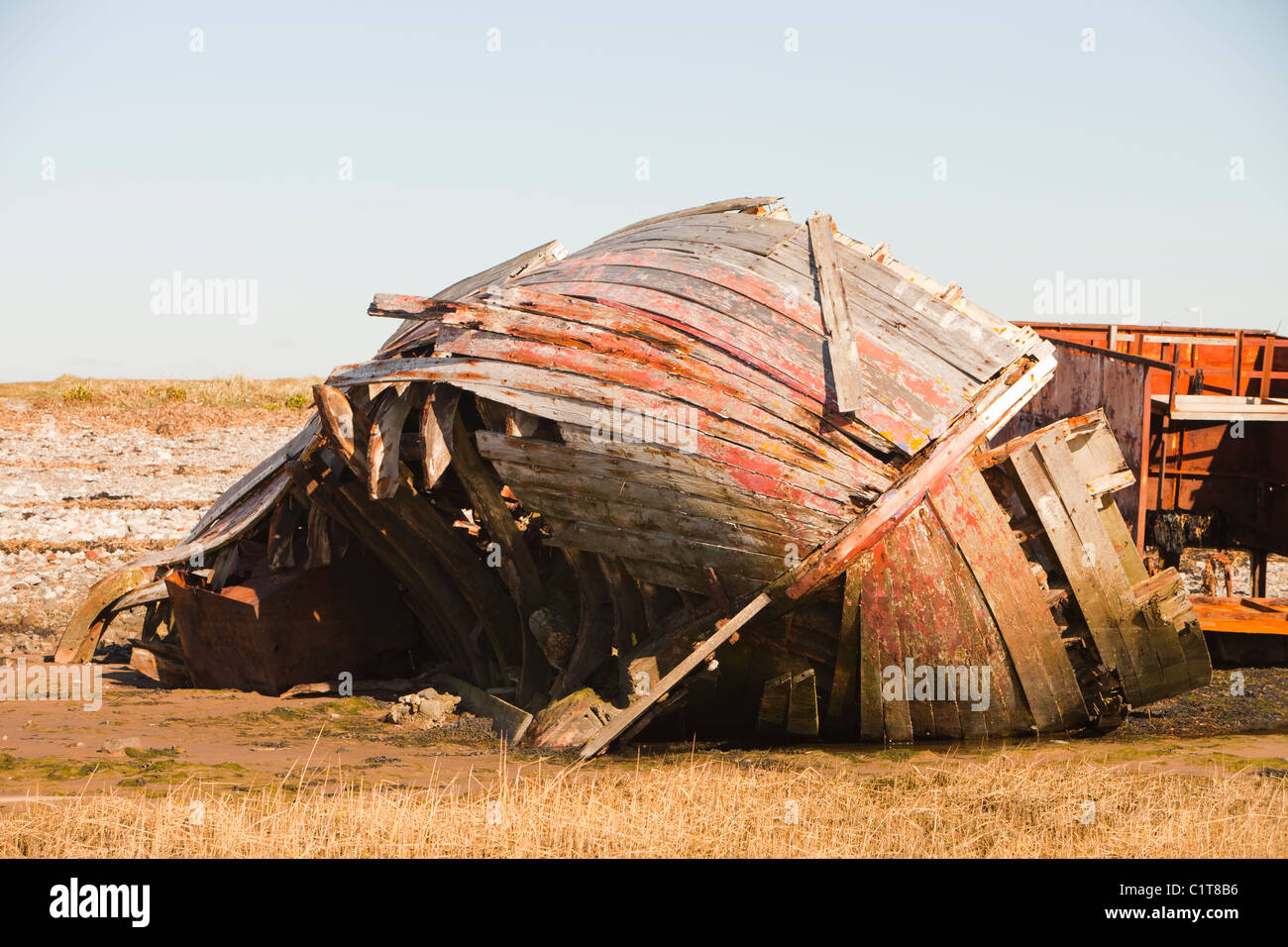 An old wooden hulled boat abandoned on the shoreline at Rampside, Cumbria, UK. Stock Photo