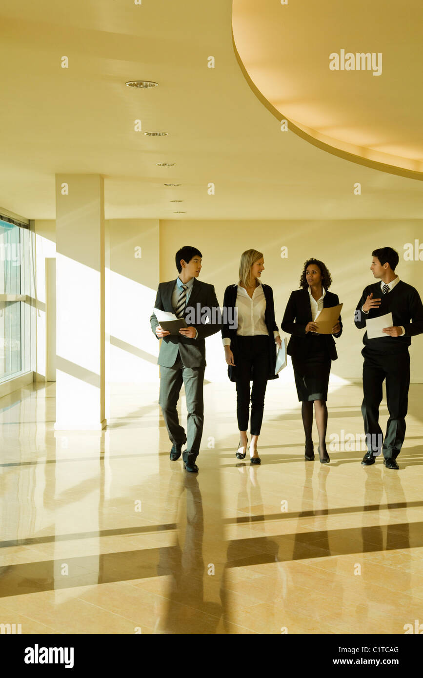 Group of executives talking as they walk together in lobby Stock Photo ...