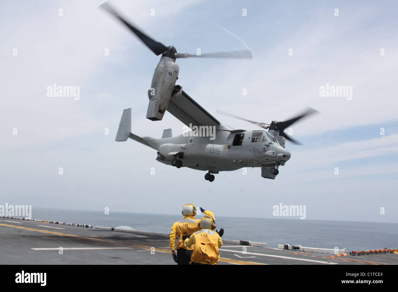 A sailor with USS Kearsarge salutes MV-22 Osprey pilots, Capt. Daniel W. Kaiser and Capt. Brandon L. Whitfield, as they take off Stock Photo