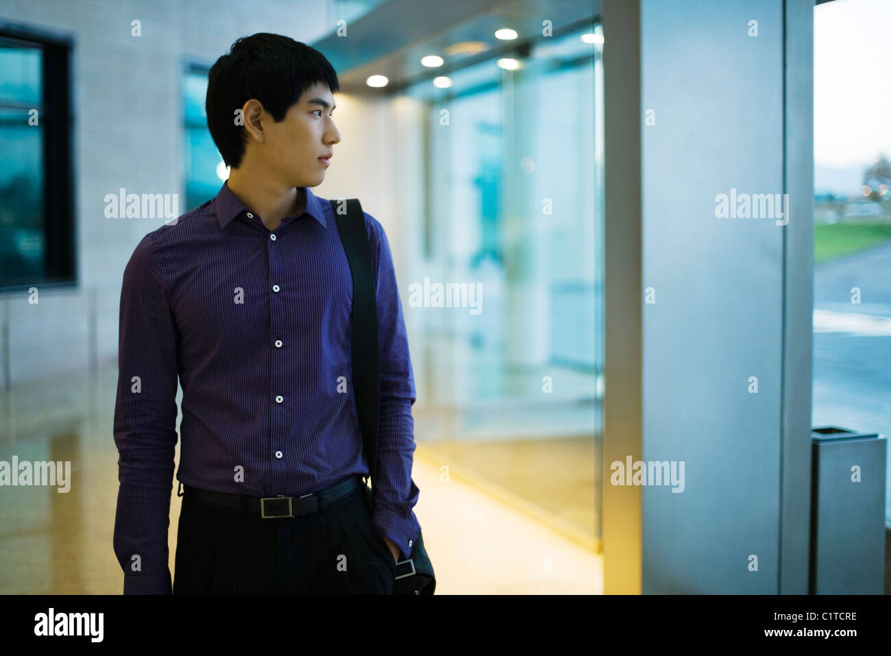 Young businessman walking in lobby, looking out window Stock Photo - Alamy