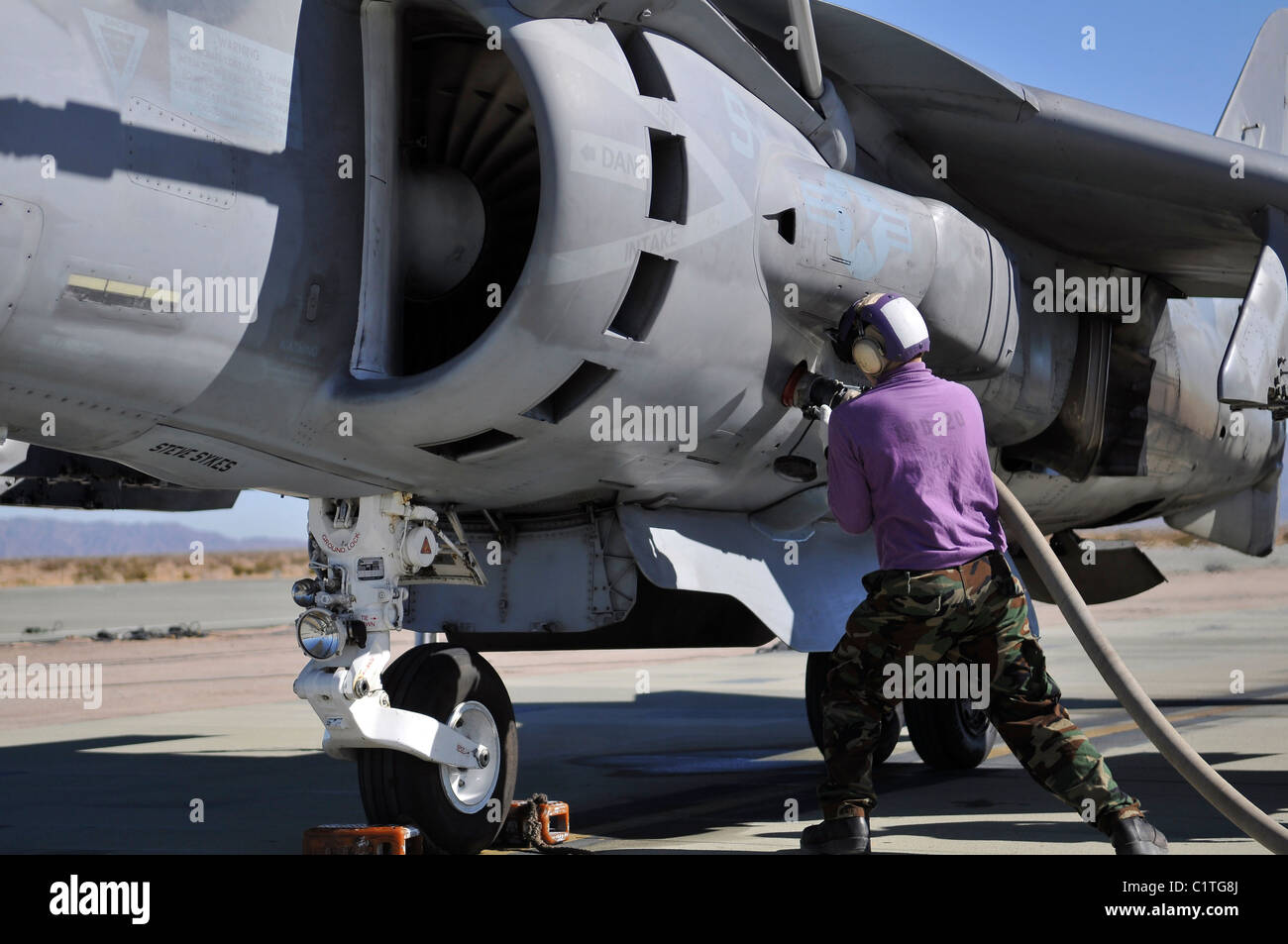 Aviation fuel technician attaches a fuel line to an AV-8B Harrier. Stock Photo