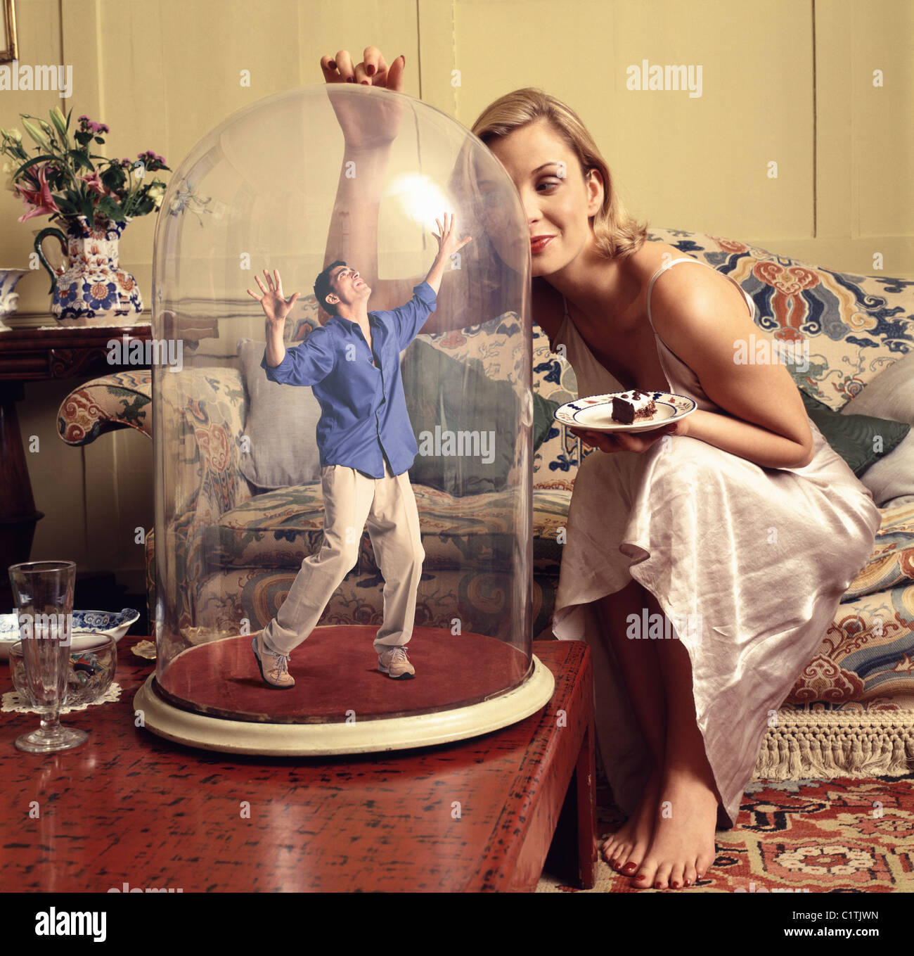 Woman with small man captured in glass jar Stock Photo