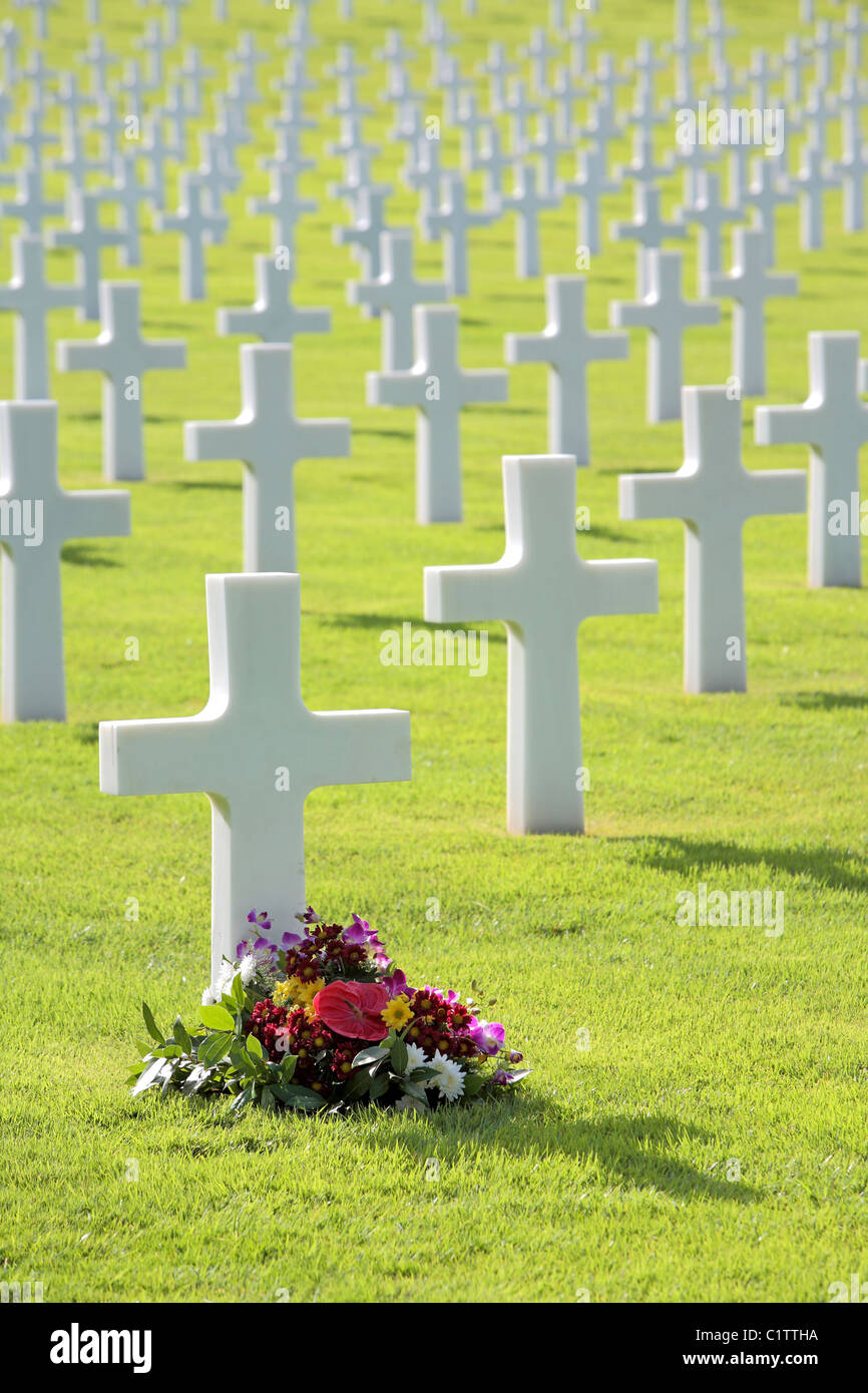 Pretty flowers laid by a cross shaped headstone in a military grave in