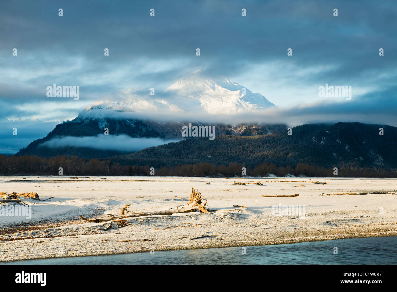 Clouds and mist enhance the sunrise on the Chilkat Mountains and Chilkat River bed outside Haines, Alaska. Stock Photo
