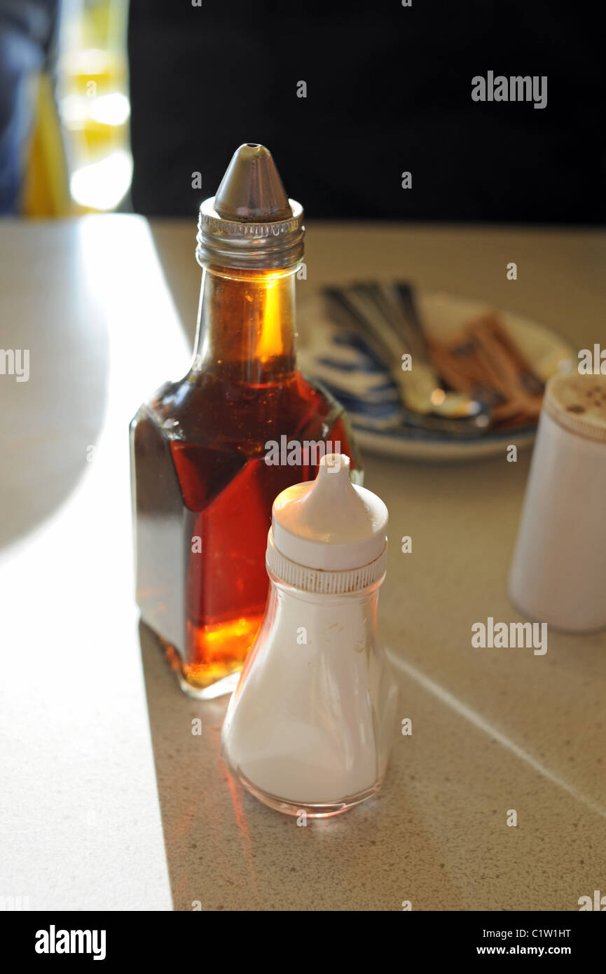 Salt and vinegar with a pot of pepper on a table condiments to eat with fish and chips UK Stock Photo