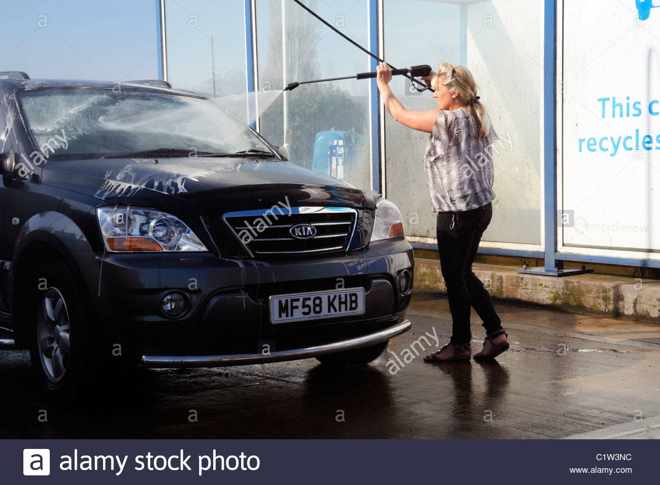 Women using a car wash to clean a Kia 4x4 chelsea tractor. Woman Stock