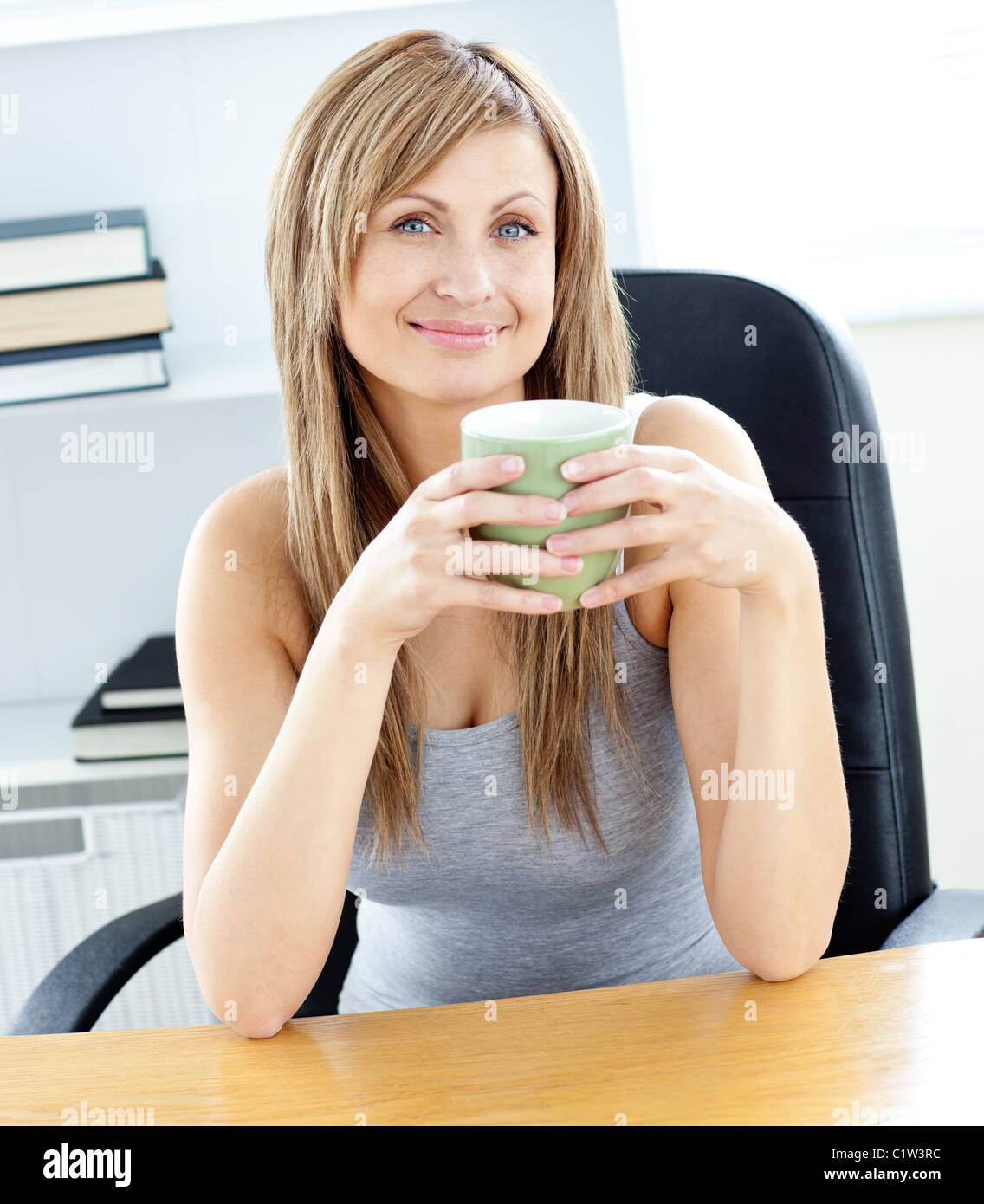 Glowing businesswoman holding a cup at her desk Stock Photo - Alamy