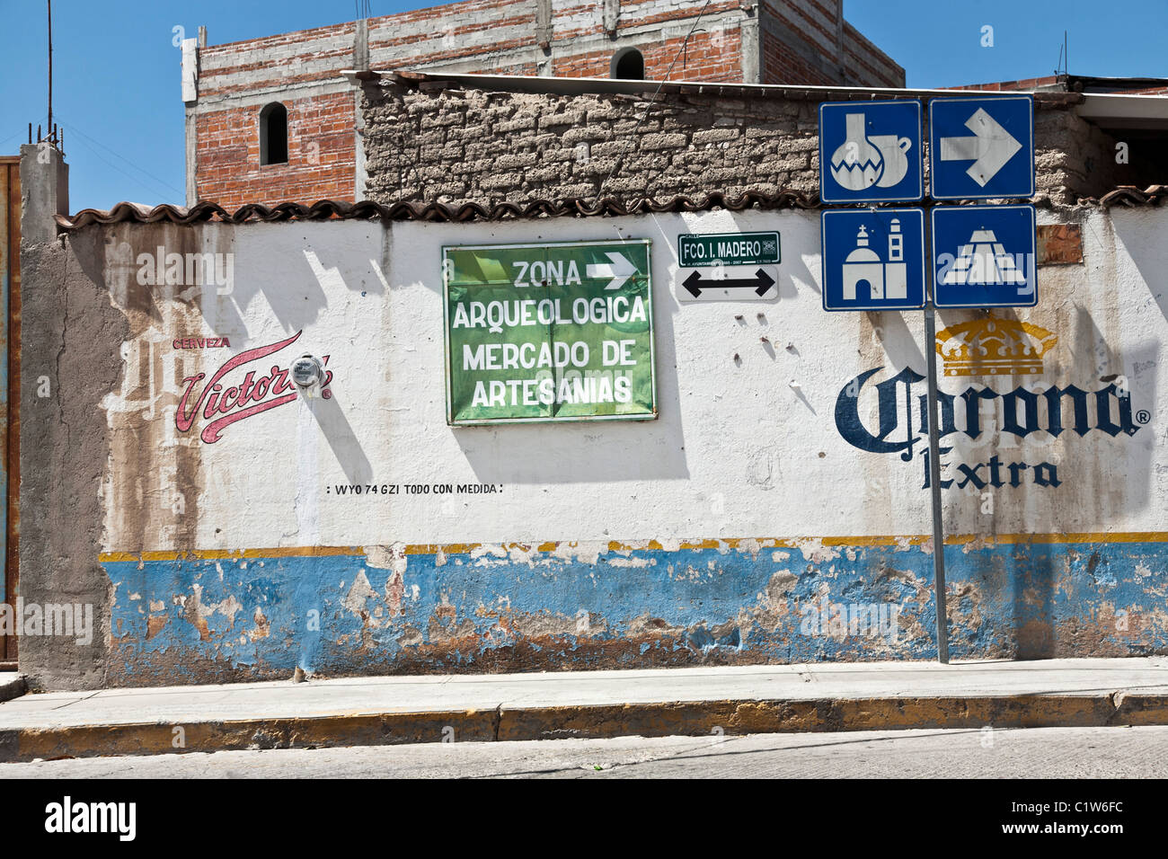 wall with old trademarks sign & handsome graphics indicating direction to Mitla archaeological zone & artisans' market Mexico Stock Photo