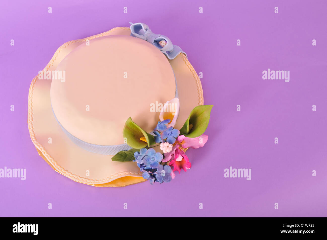 Food for Easter - Easter Cake shaped like an Easter Bonnet Hat with fondant icing and sugar paste flowers isolated on purple Stock Photo