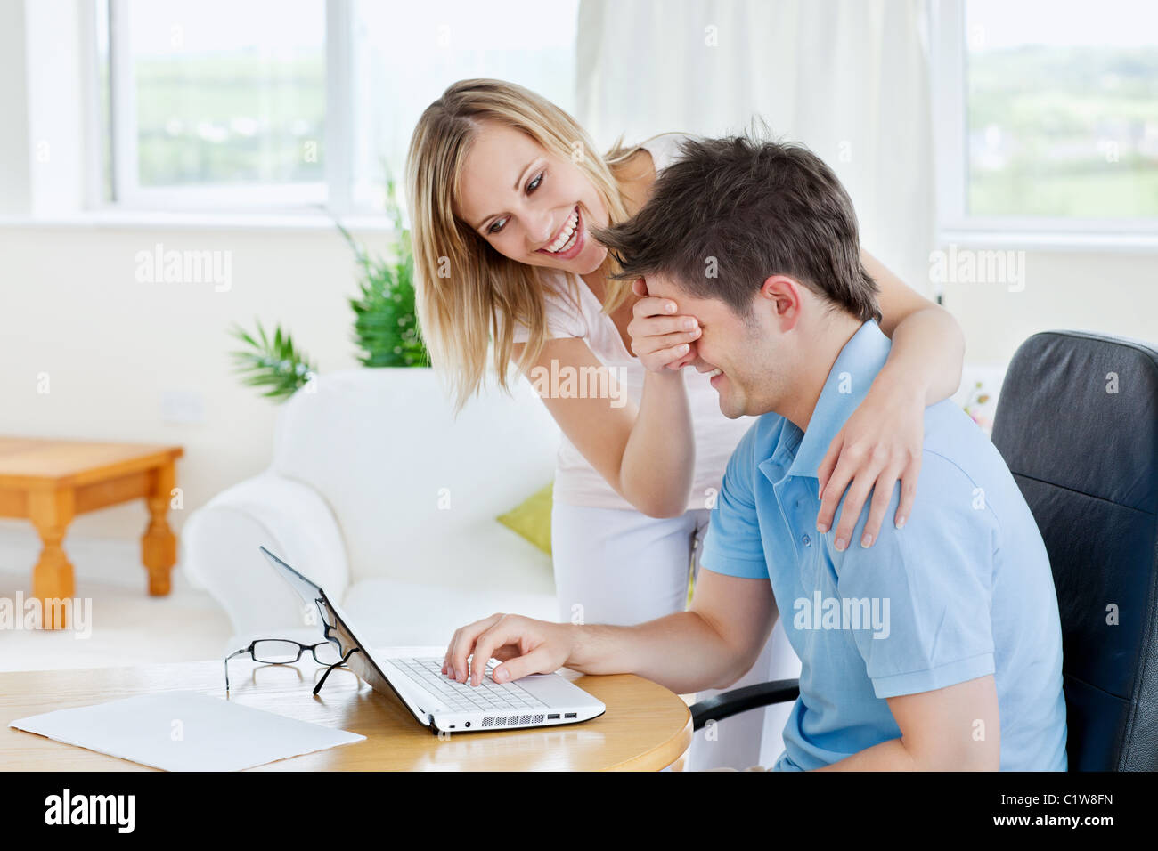 Bright couple having fun in front of a laptop Stock Photo - Alamy
