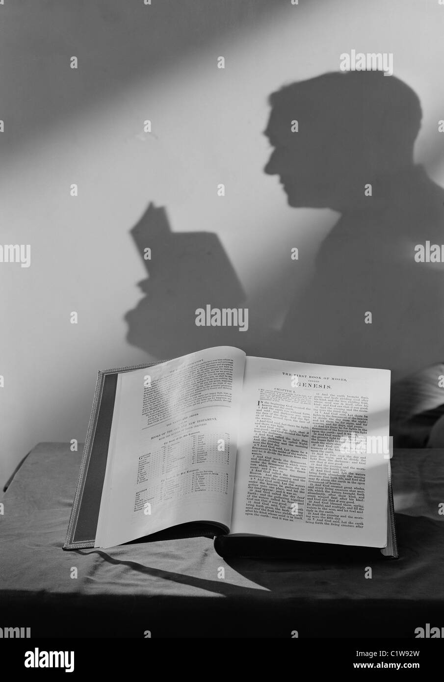 Shadow of man reading open bible Stock Photo