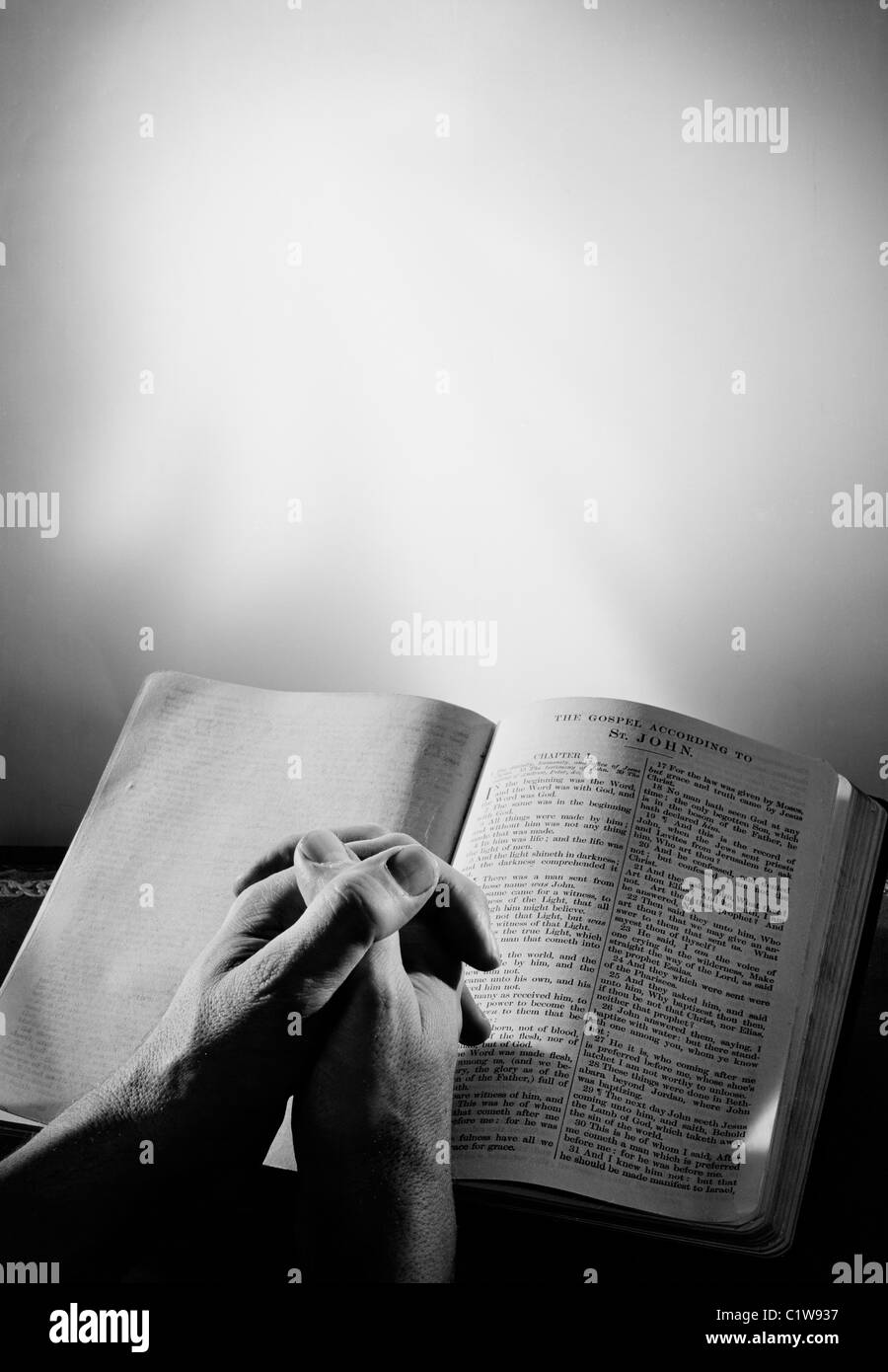 Mans hands clasped by bible Stock Photo