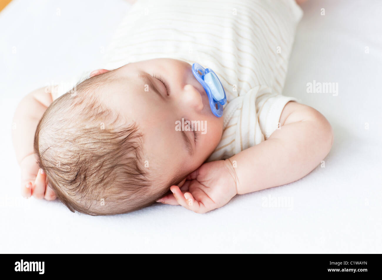 Portrait of an adorable baby with a pacifier sleeping in a bed Stock