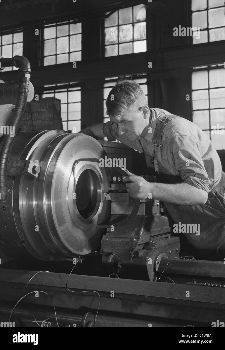 Operator gauging work in a high speed engine lathe. Stock Photo