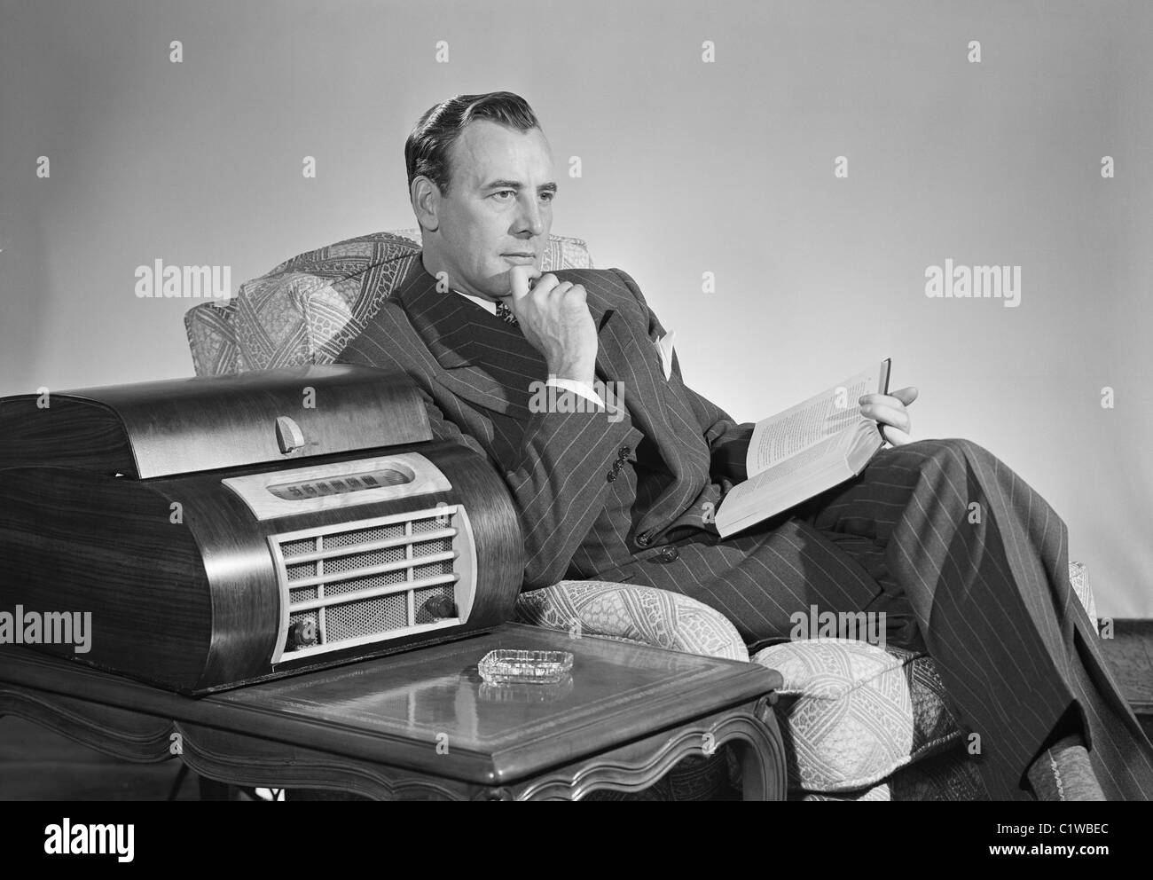 Mid adult man sitting in an armchair and listening to music Stock Photo