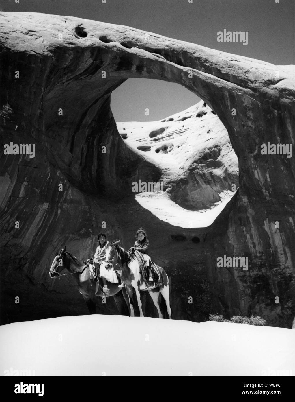 USA, Arizona, Monument Valley, man and child riding horses by rock formation Stock Photo