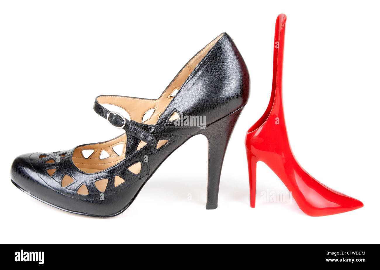 Black feminine loafer and red shoehorn in the manner of red feminine small shoe on white background Stock Photo