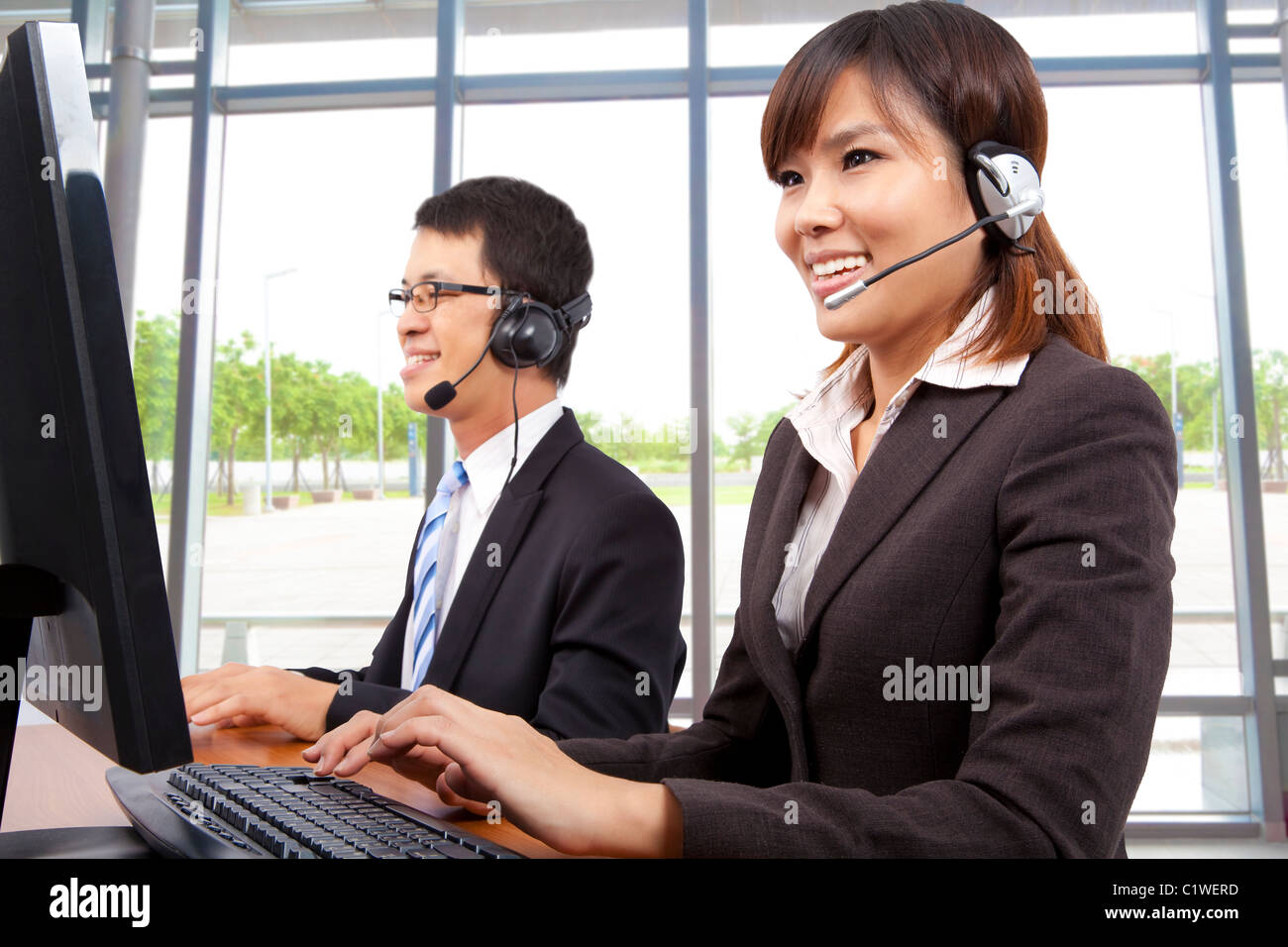 Smiling customer service representative in modern office with a headset Stock Photo