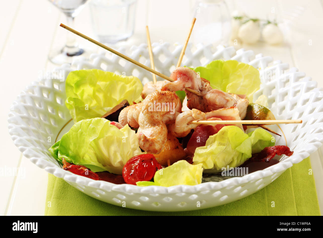 Roasted chicken skewers and bacon served on lettuce leaves Stock Photo