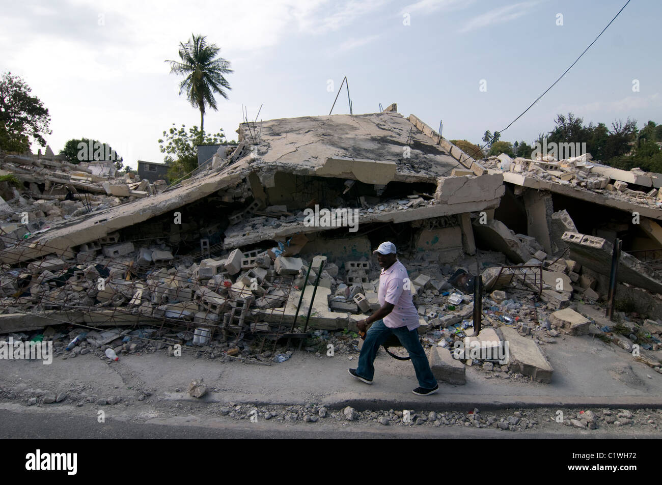 Pedestrian walks past a building that collapsed in Port-au-Prince after ...