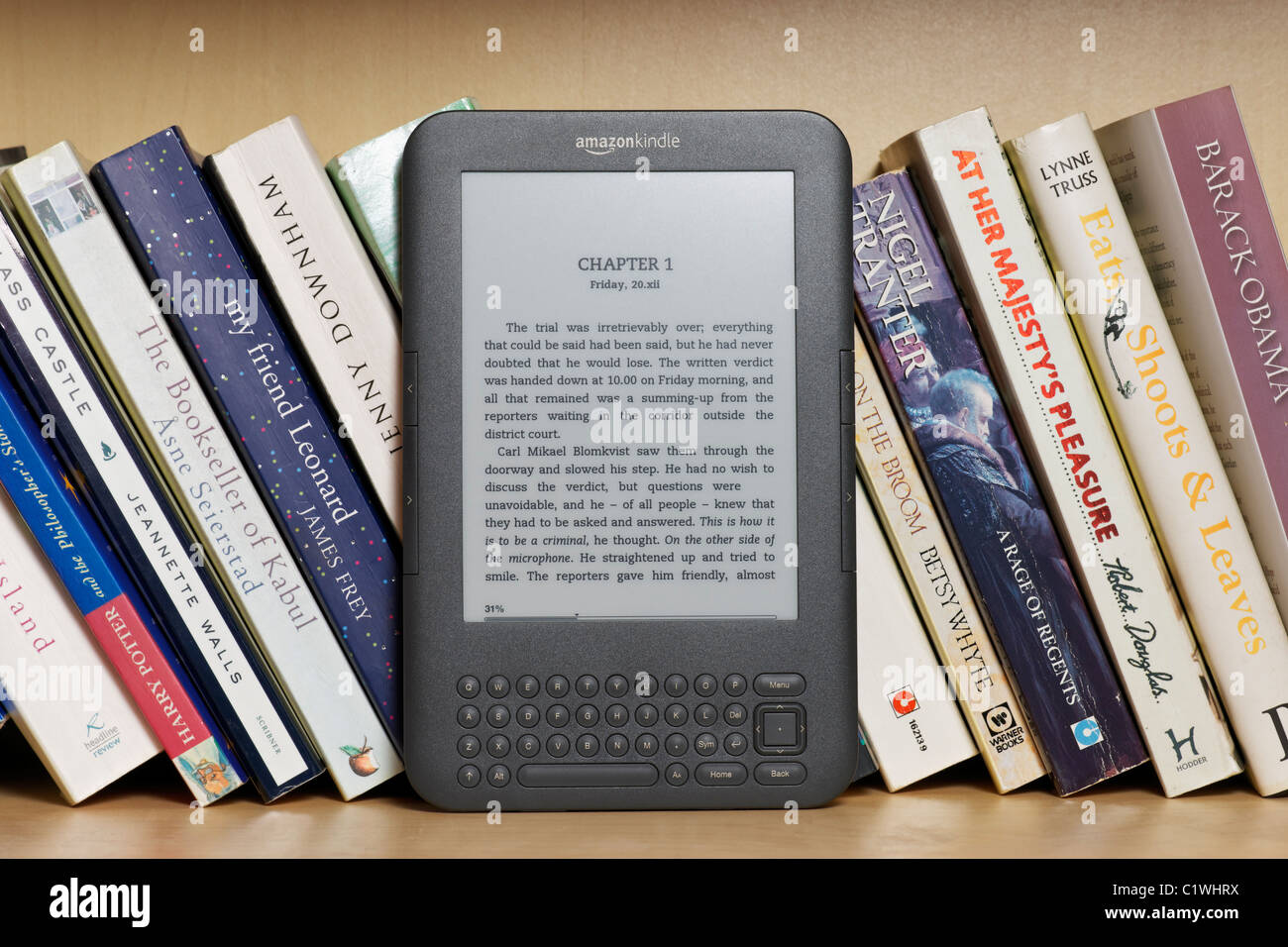 An Amazon Kindle Ebook Reader On A Bookshelf With Paperbacks This