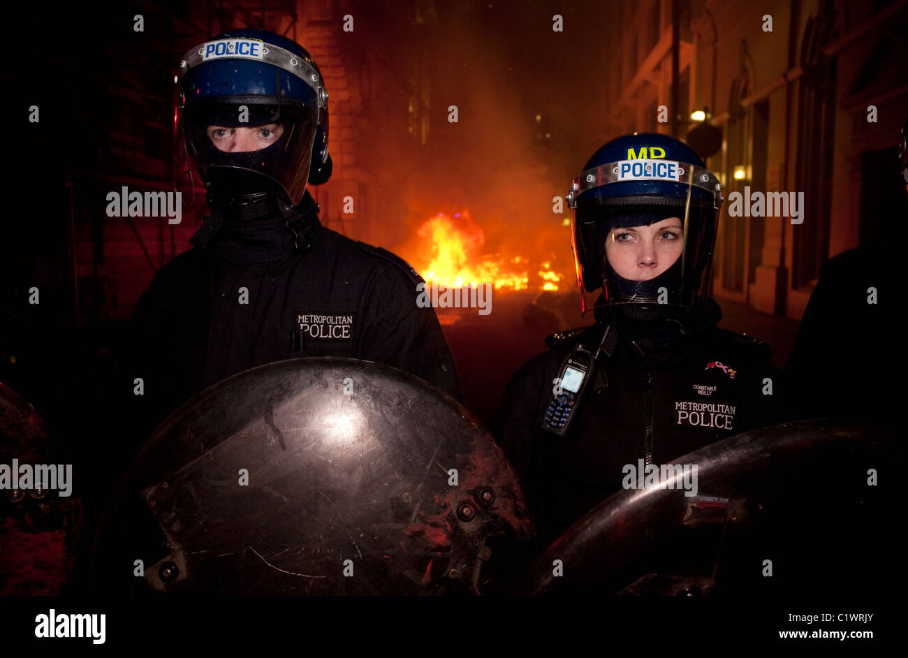 Anti-Cuts march 26/03/2011, London,  Police stand guard on Jermyn St as fire set by protestors rages in distance. Stock Photo