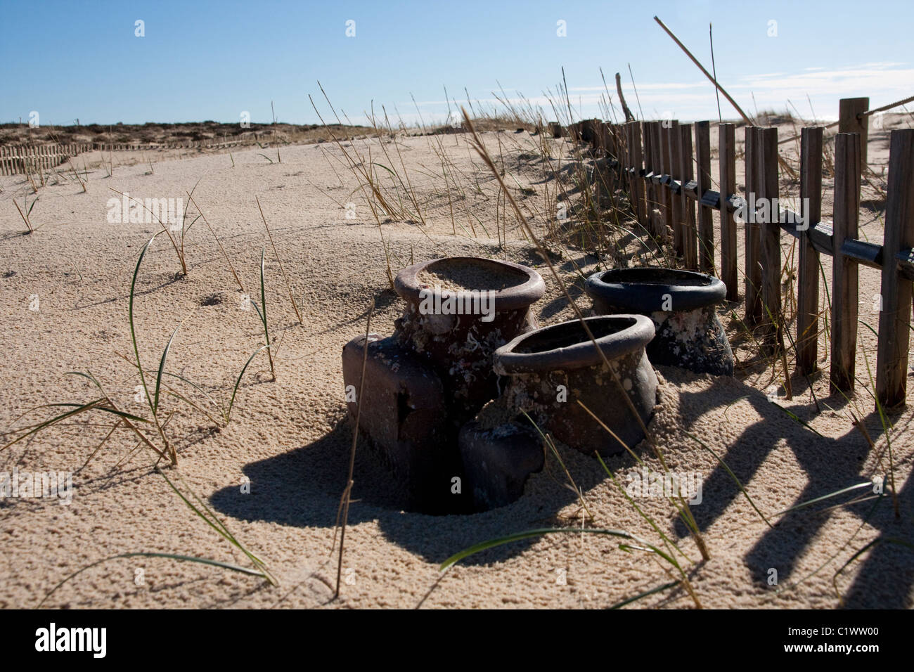 View of a section of a fence buried on the sand making a shadow. Stock Photo