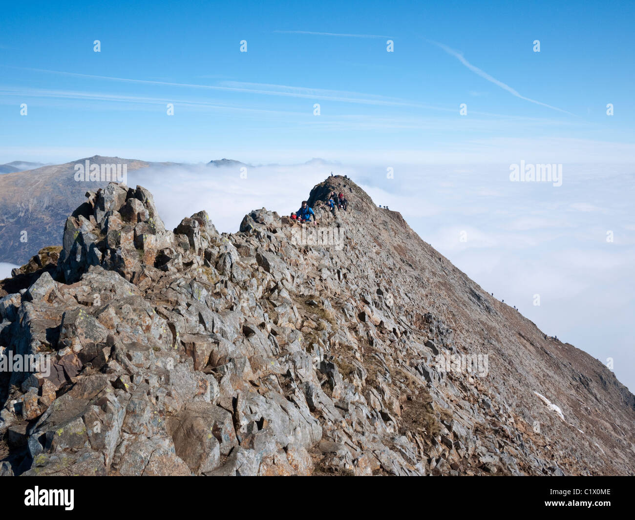 Scramblers on the knife edge arete of Crib Goch above a cloud inversion on the classic Snowdon Horseshoe route. Stock Photo