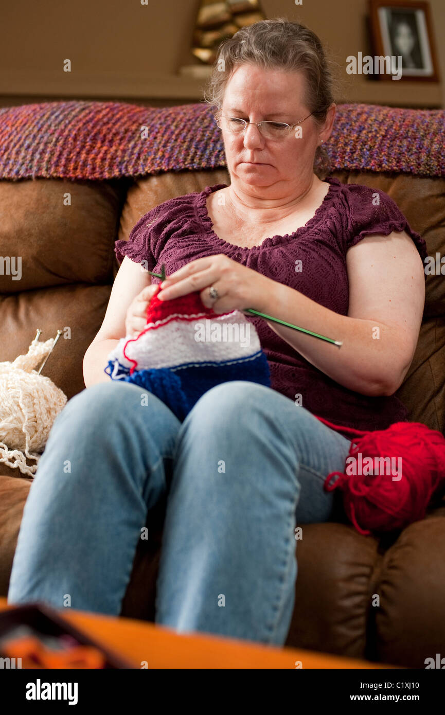 Mature woman on couch concentrating on her knitting Stock Photo - Alamy