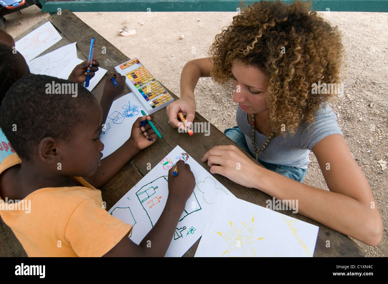Noa Yaakov Israeli volunteer of Natan International Humanitarian Aid drawing with young orphans during art therapy session in a makeshift camp for survivors of a 7.0 magnitude earthquake which struck Haiti on 12 January 2010 in  the outskirts of Port-au-Prince Stock Photo