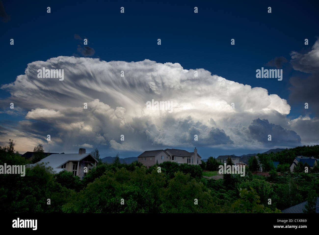 A massive summer cumulonimbus cloud over an exurban neighborhood in the Wasatch Range, Utah. Stock Photo