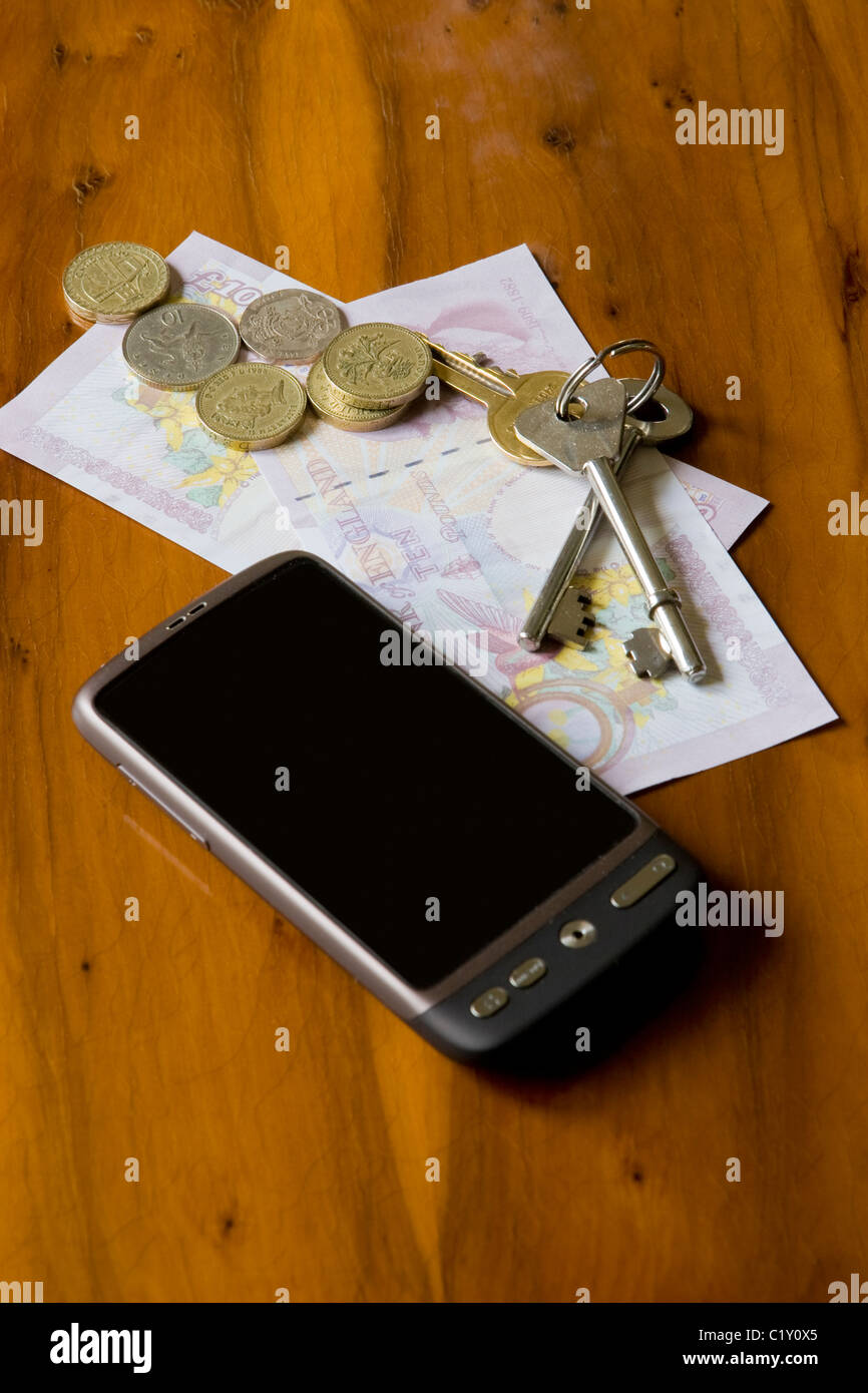 Mobile smartphone with sterling cash and a bunch of keys on a wooden table Stock Photo