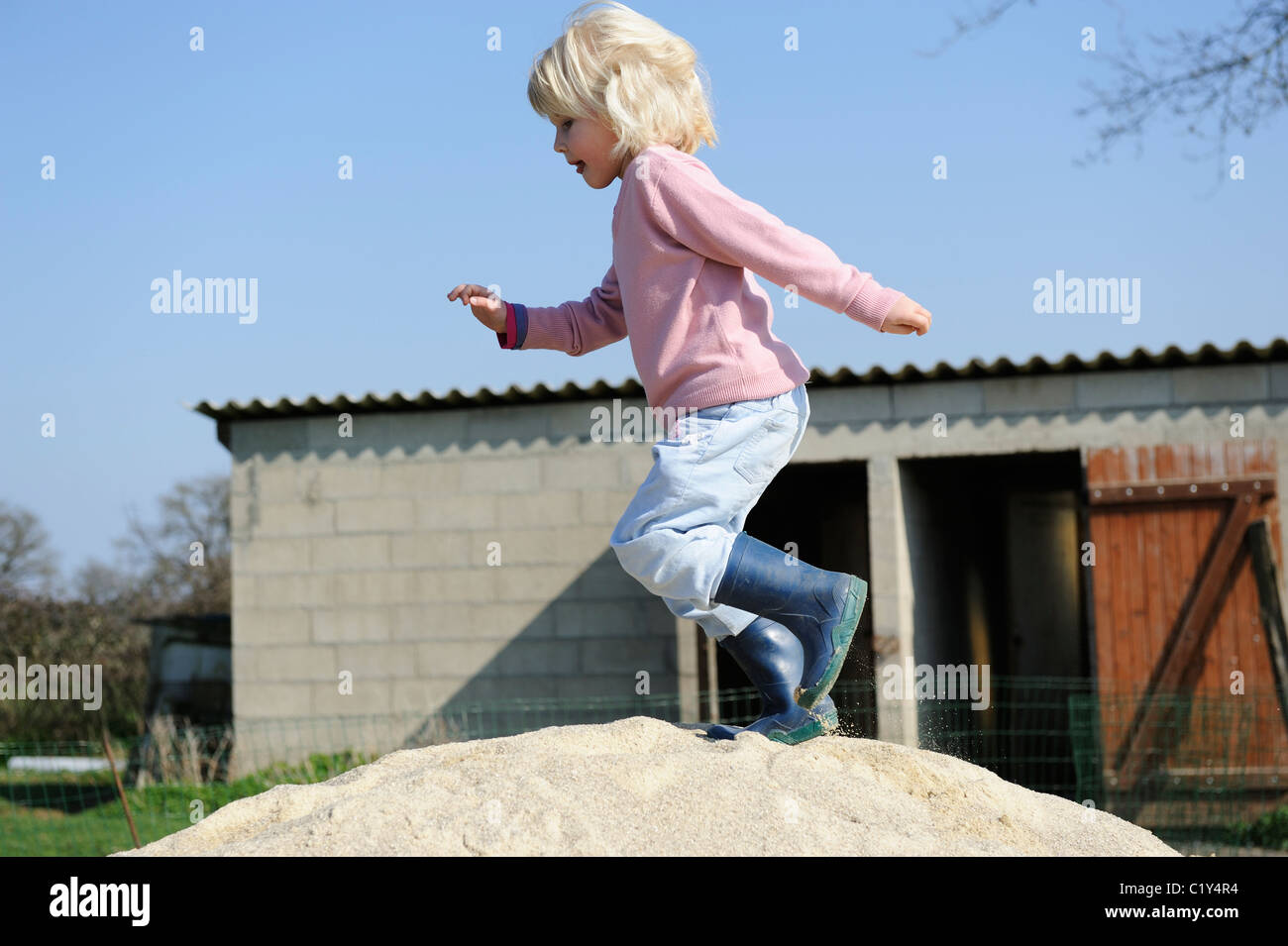 Stock Photo of a Five Year old Girl Running Across a Pile of Sand. Stock Photo
