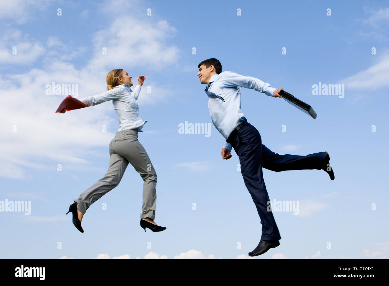 Portrait of happy partners jumping against blue sky Stock Photo - Alamy