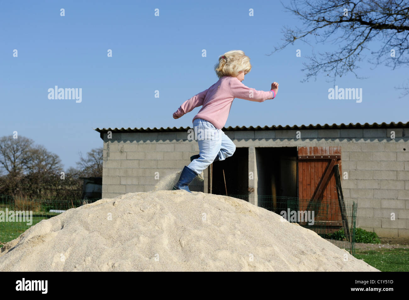 Stock Photo of a Five Year old Girl Running Across a Pile of Sand. Stock Photo