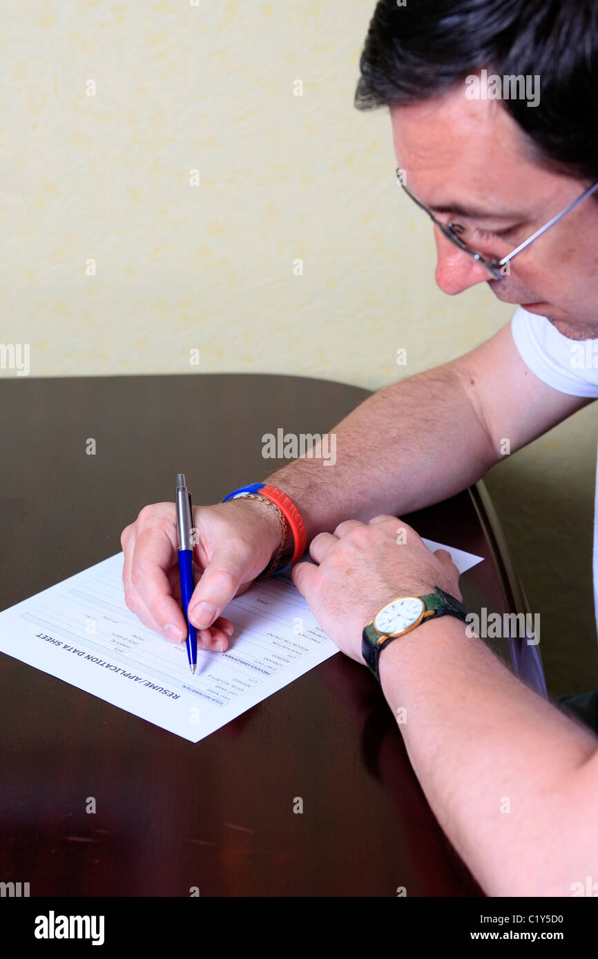 Adult man sitting at home filling out a job application form Stock Photo