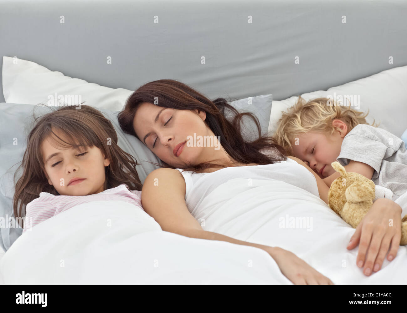 Adorable children sleeping with their mother on her bed Stock Photo Alamy