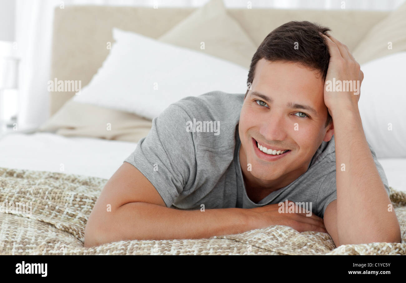 Joyful man lying on th edge of his bed at home Stock Photo Alamy