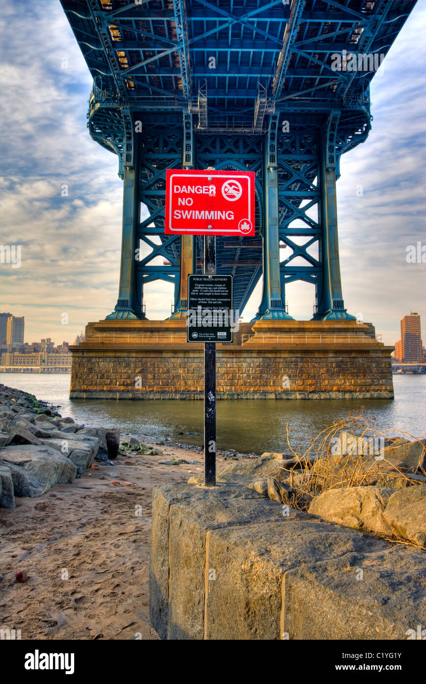 No Swimming sign under the Manhattan Bridge in Brooklyn at sunrise Stock Photo