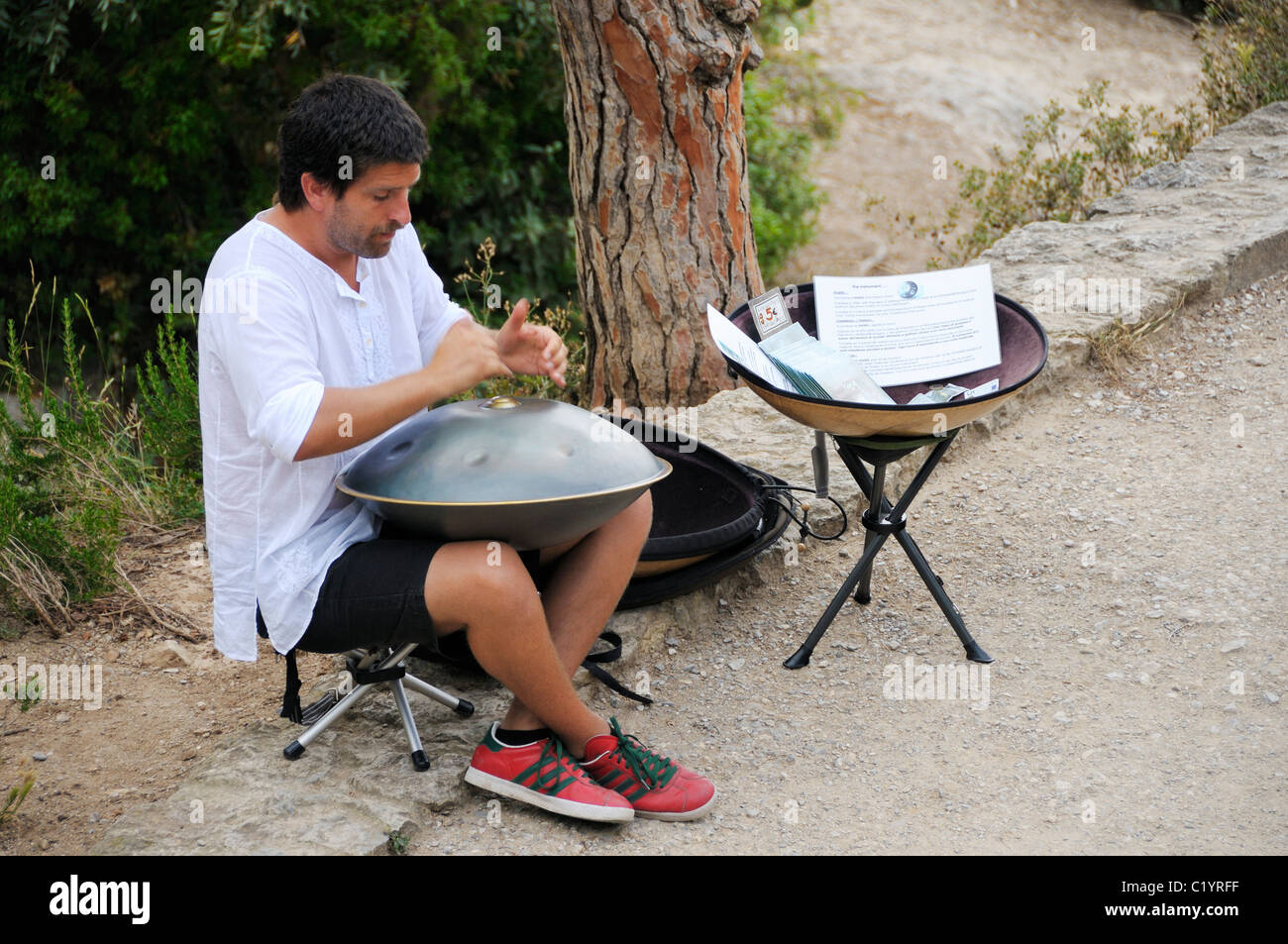A musician playing his hang (Swiss made metal music instrument) in Parc Guell, Barcelona, Spain. Stock Photo