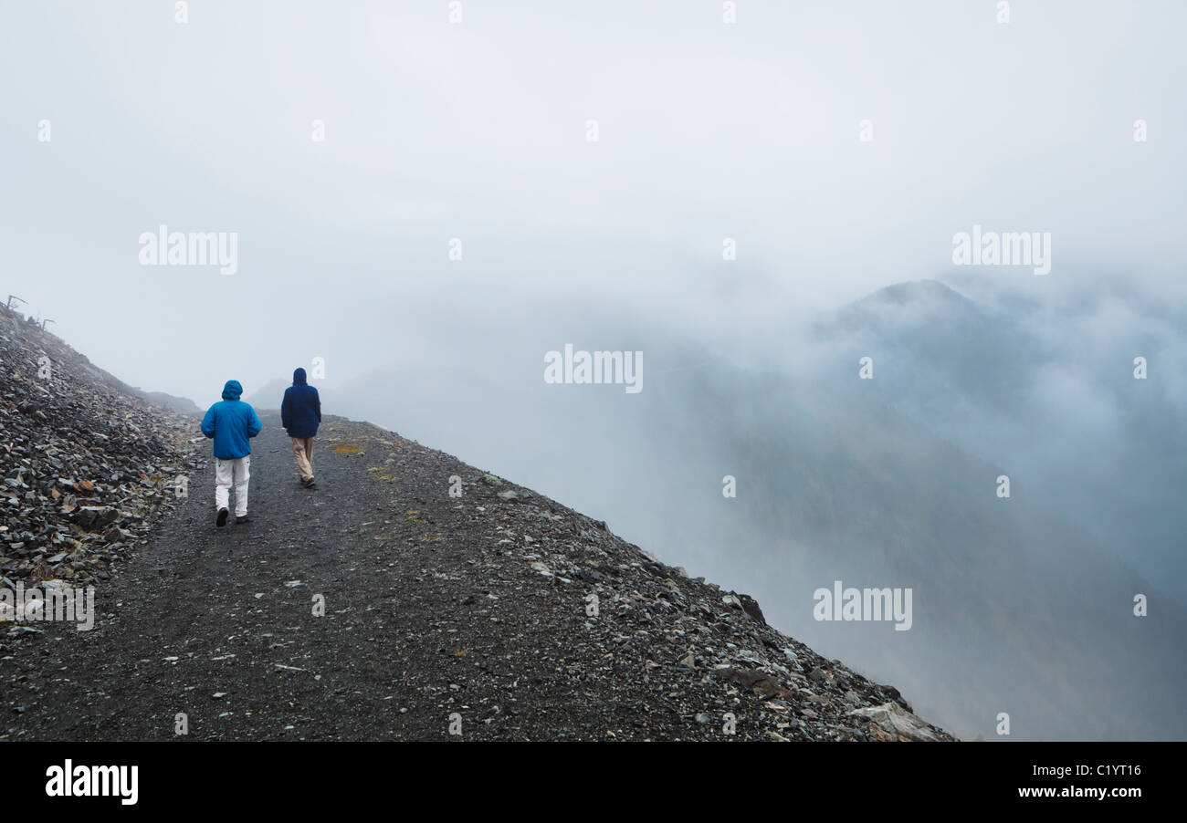 Two men walking down a road on Slate Peak on a cloudy rainy day in the North cascades of Washington, USA. Stock Photo